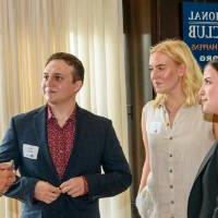 Group of 4 alumni stand in circle and talk at event